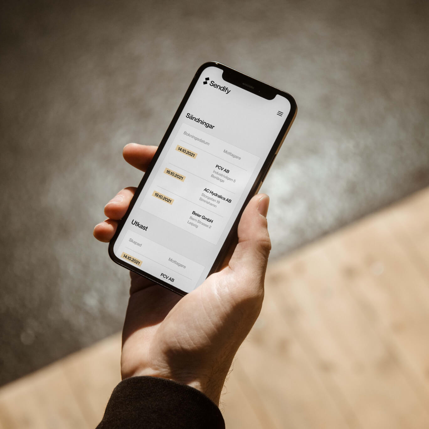 En hand som håller i en telefon med Sendify i webbläsaren.