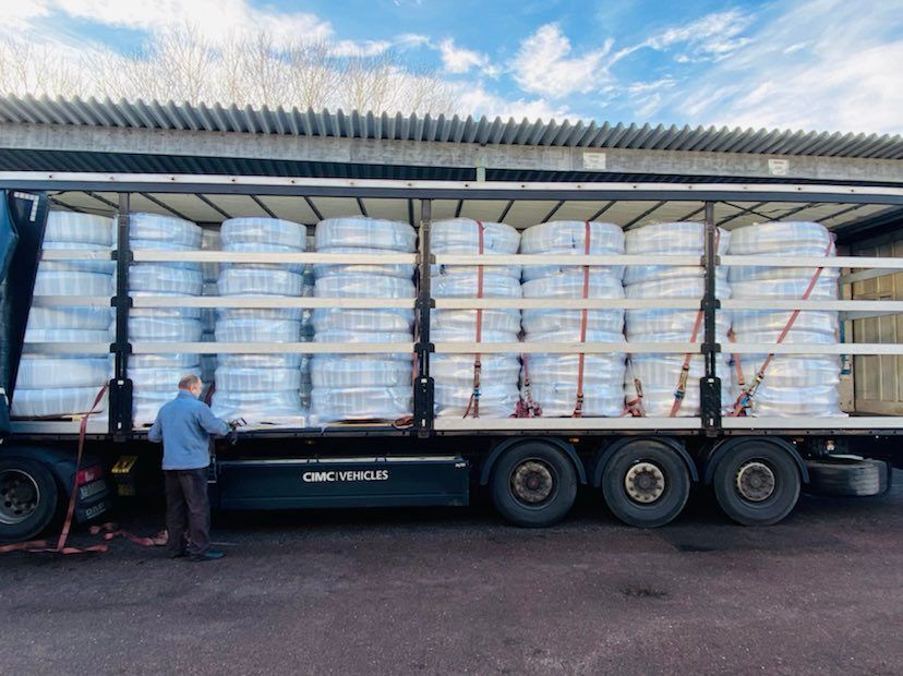 Inplastade rullar med slang staplade på EU-pallar, lastade på ett lastbilsflak.