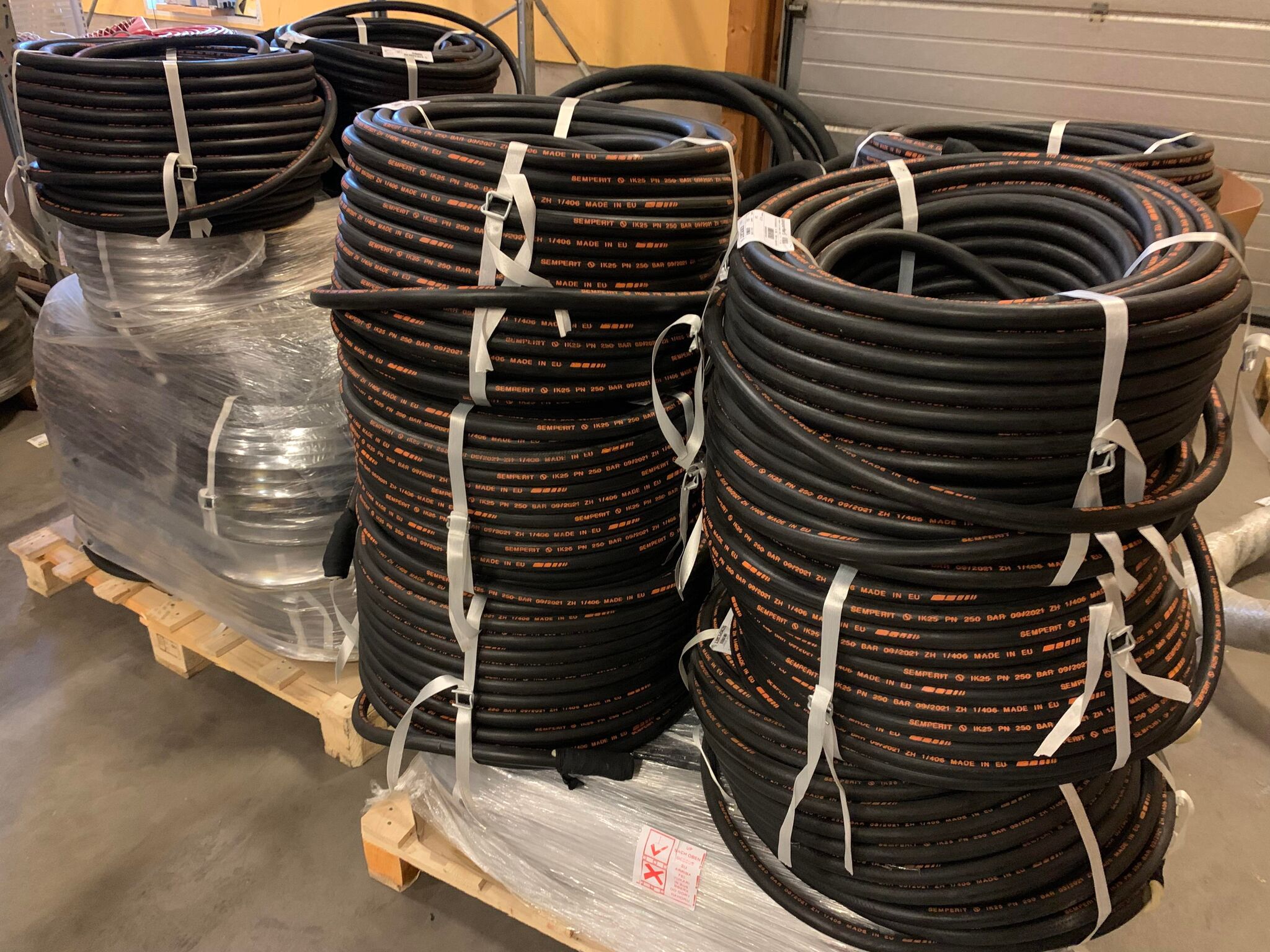 Svarta slangar på rulle staplade på varandra på en EU-pall