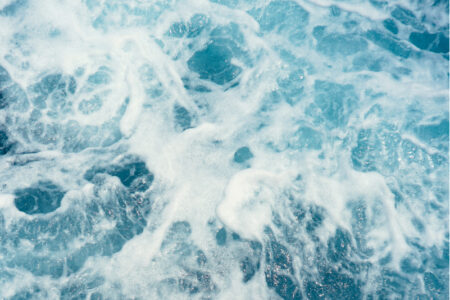 Närbild på klarblått hav och vågor som skummar.