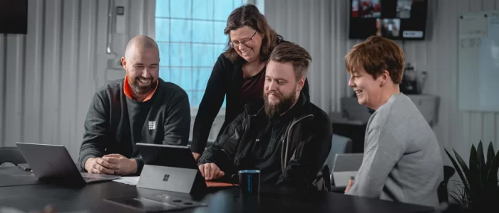 Ett gäng kollegor som samlats kring en dator i ett konferensrum