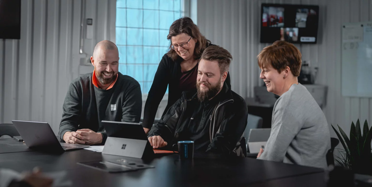 Ett gäng kollegor som samlats kring en dator i ett konferensrum