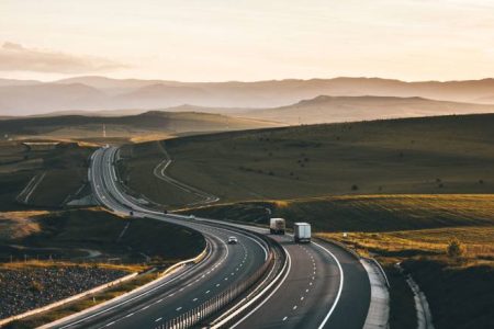 A road leading into the horizon with trucks.