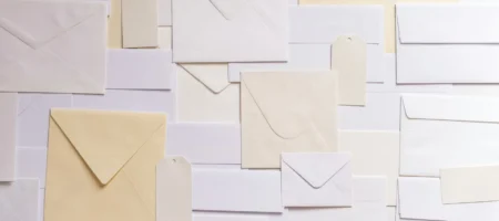 Flera brev i olika storlekar i vitt och beige som ligger ned på en plan yta.